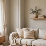 A living room wall painted in warm greige BM Edgecomb Gray with white trim and wood furniture