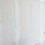 A freshly primed new drywall wall with white primer applied evenly over taped seams.