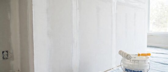A freshly primed new drywall wall with white primer applied evenly over taped seams.